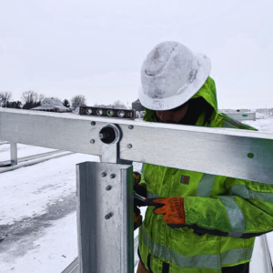 Solar construction technician aligning racking connection on a ground mounted solar system